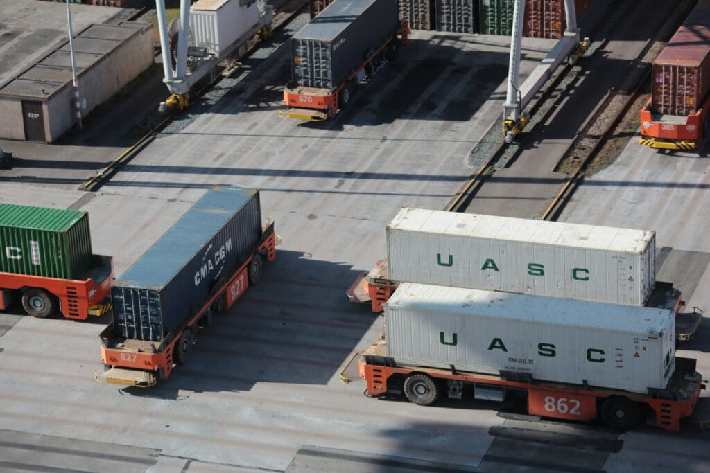 Containertransport im Logistikzentrum mit Lkw und Ladeeinheiten zur Absicherung von Waren über eine Transportversicherung