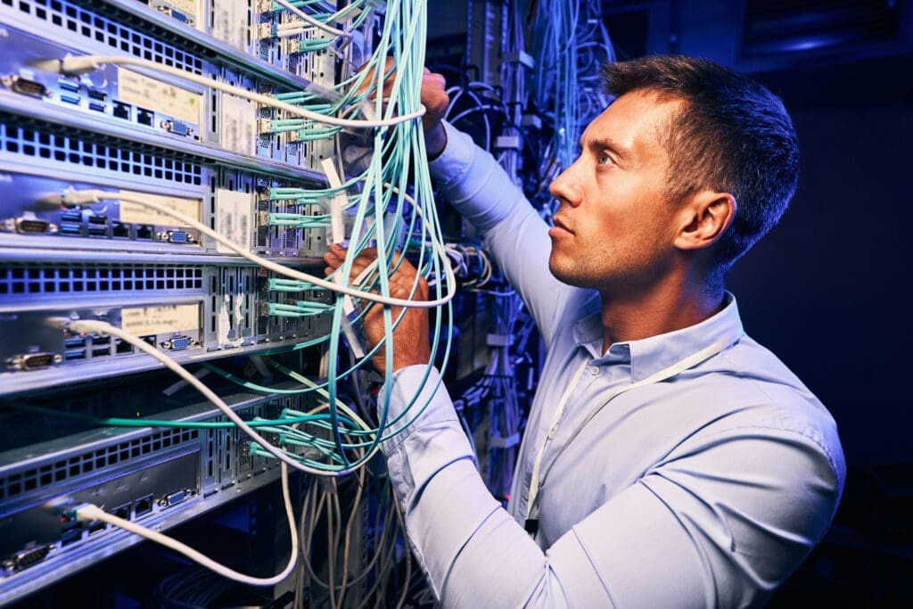 IT-Techniker prüft Server- und Netzwerkinfrastruktur im Rechenzentrum zur Sicherung von Systemstabilität und Schutz vor Betriebsunterbrechungen durch Cyberangriffe