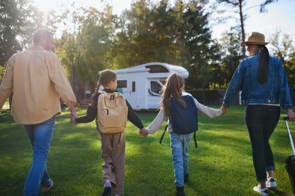 Familie mit Kindern kommt mit einem Wohnmobil auf einem Campingplatz an, unterwegs im Urlaub mit Camper.