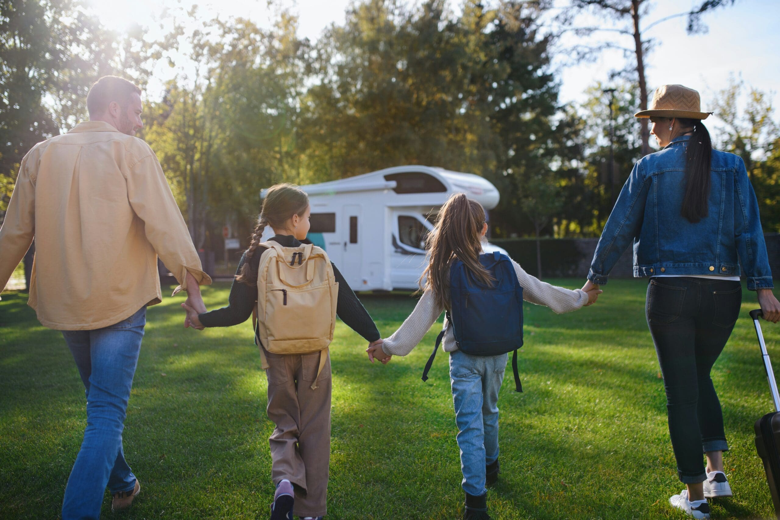 Familie mit Kindern kommt mit einem Wohnmobil auf einem Campingplatz an, unterwegs im Urlaub mit Camper.