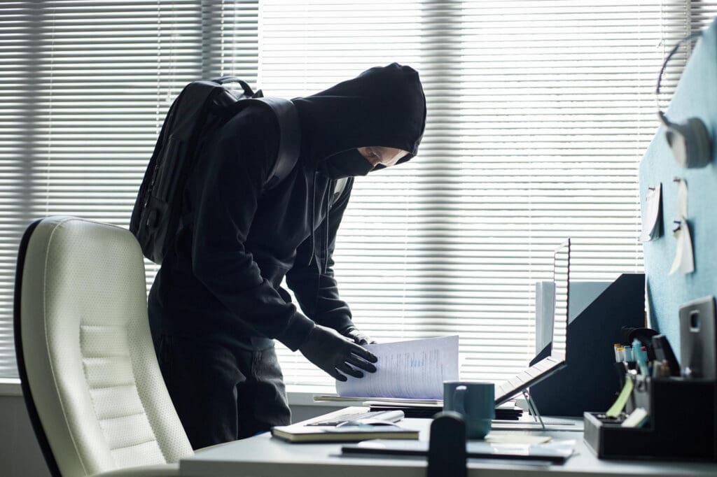 Unbefugte Person durchsucht vertrauliche Unterlagen am Arbeitsplatz – Darstellung von Vertrauensschäden, Datenmissbrauch und wirtschaftlichen Risiken für Unternehmen