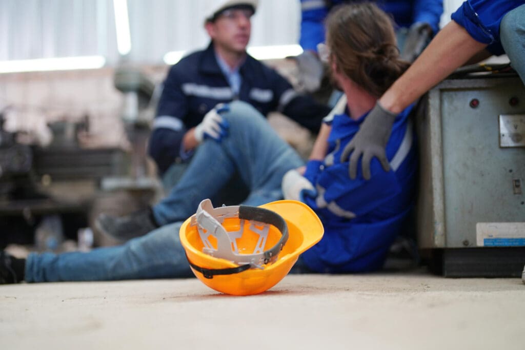 Arbeitsunfall im Betrieb: gestürzter Mitarbeiter wird von Kollegen versorgt – Absicherung durch eine Gruppenunfallversicherung